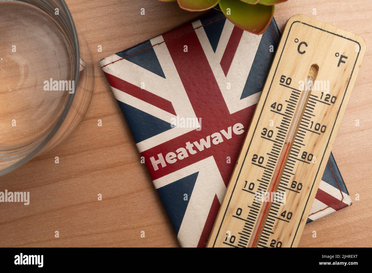 Uk heatwave concept: leather wallet with union jack flag and a thermometer on a wooden table Stock Photo
