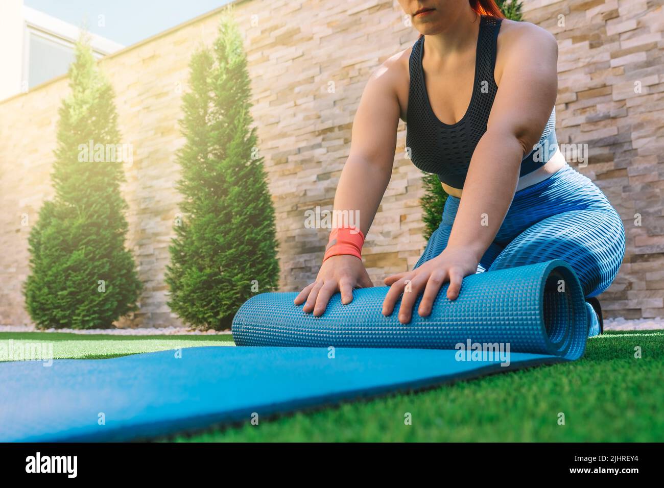 cropped shot of a young sportswoman, unrolling a mat for yoga exercises