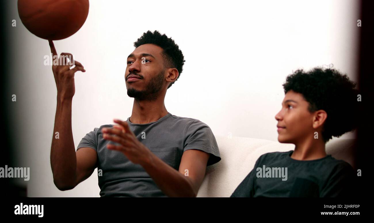 Older brother teaching younger sibling to spin basketball with finger