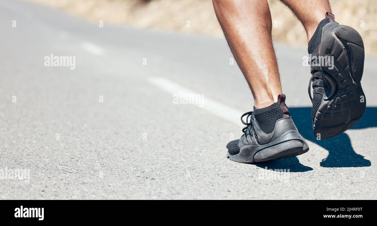 Rear View closeup of an unrecognisable man running outdoors. Unknown fit mixed race male jogging on a road outside during his daily workout routine Stock Photo
