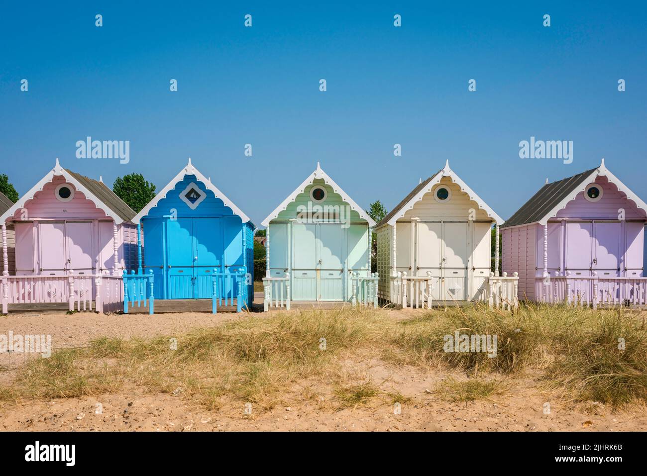UK traditional summer holiday, view in summer of a colorful beach hut under a clear blue sky, West Mersea, Essex, England, UK Stock Photo