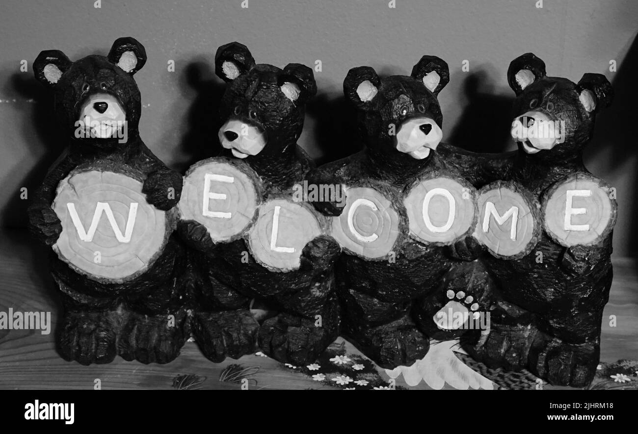 A grayscale closeup of toy bears holding a Welcome sign Stock Photo
