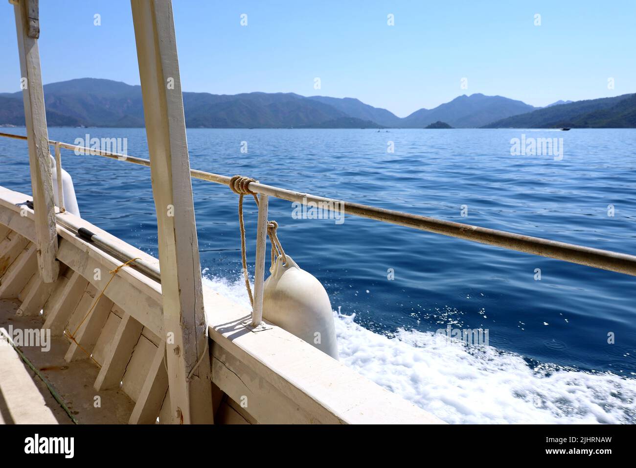 View from side of white wooden boat to Mediterranean sea with mountain islands. Water travel, summer vacation Stock Photo