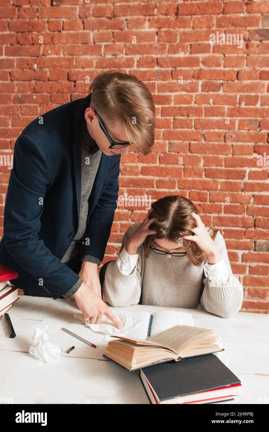 Teacher standing at desk behind tired student Stock Photo Alamy