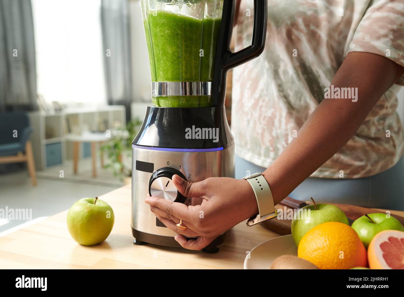 Close-up of young girl turning on the button on blender to make green ...