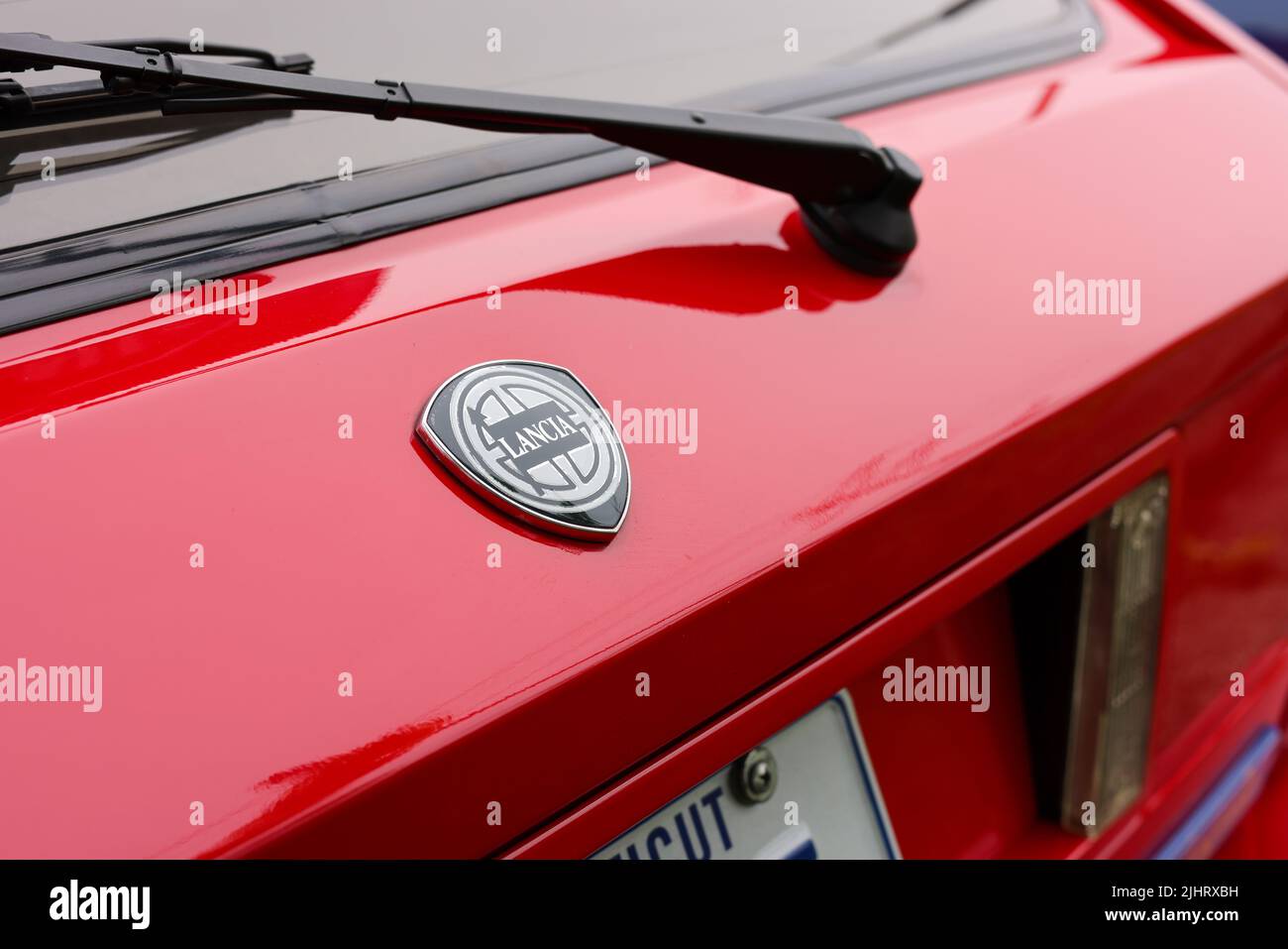 A close-up of a black and white Lancia badge on a red car Stock Photo