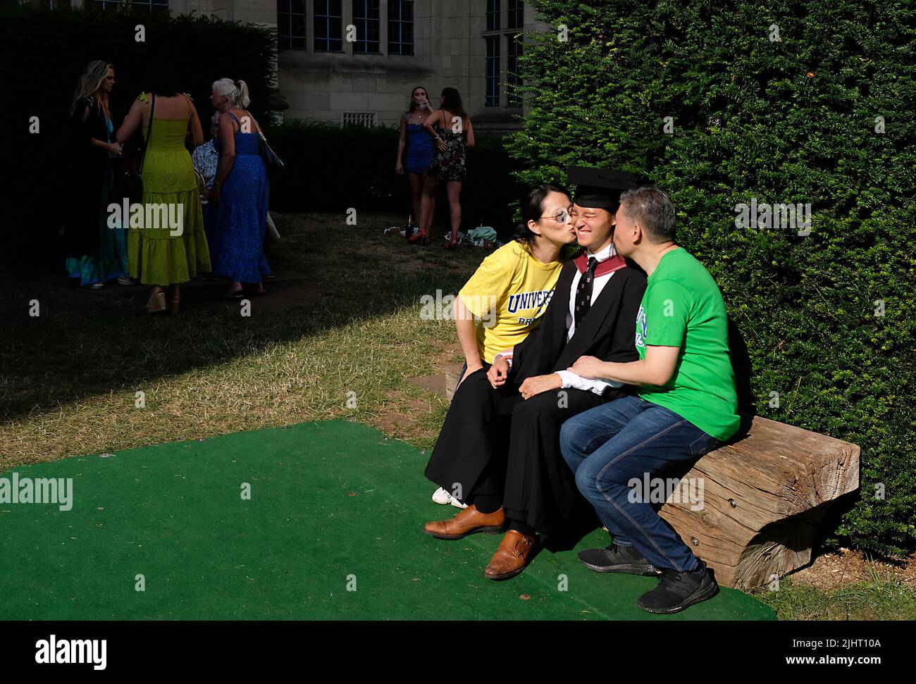 Proud Chinese parents kissing their son on his graduation day. Stock Photo