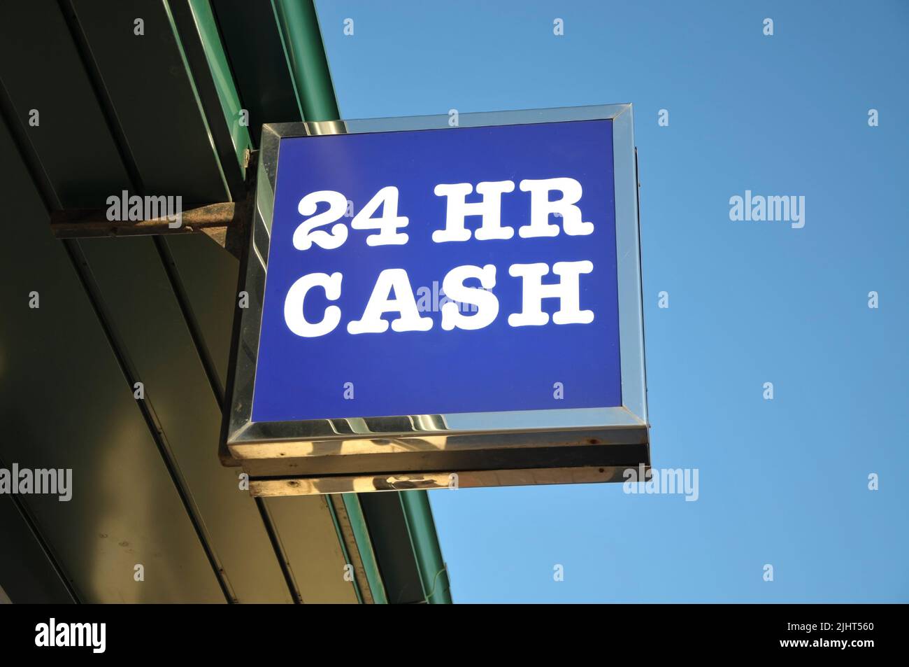 Low angle view of ATM - 24 HR CASH sign attached to building against a clear blue sky. Stock Photo