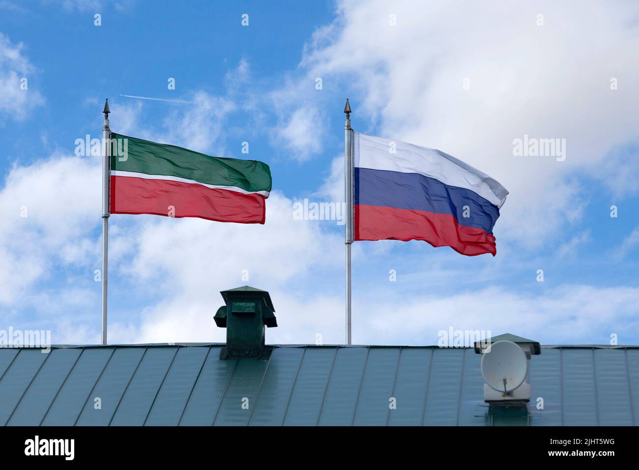 Flag of the Republic of Tatarstan next to the flag of the Federation of Russia waving atop of their poles. Stock Photo