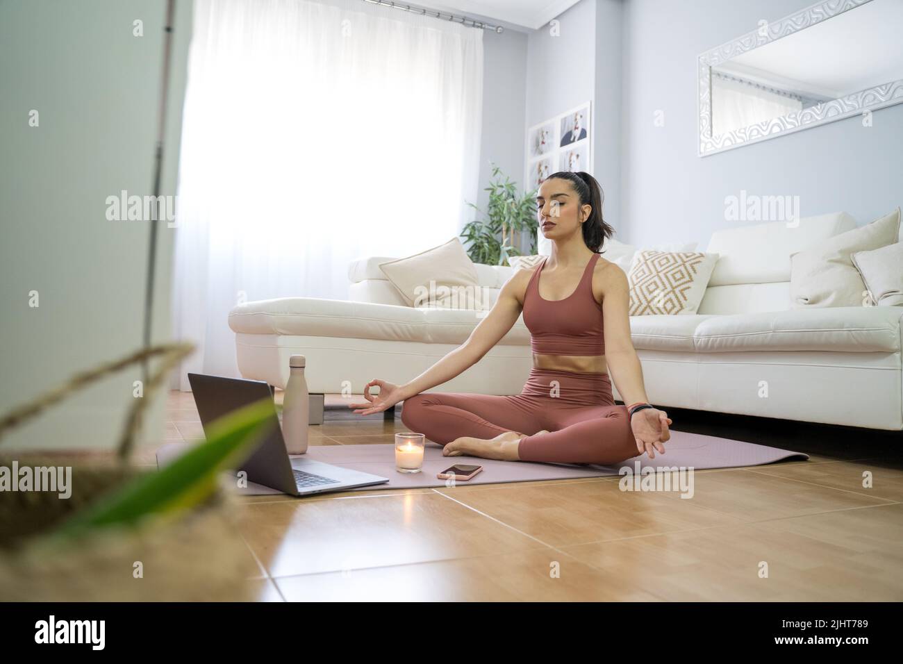 YOUNG GIRL DOING YOGA AND PILATES IN THE LIVING ROOM OF HER HOME WITH ...