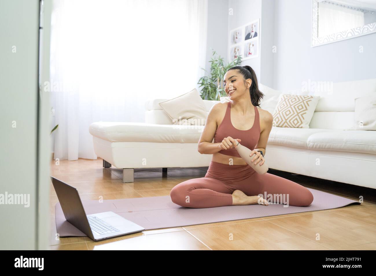 YOUNG GIRL DOING YOGA AND PILATES IN THE LIVING ROOM OF HER HOME WITH ...