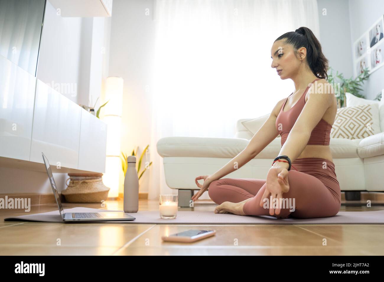 YOUNG GIRL DOING YOGA AND PILATES IN THE LIVING ROOM OF HER HOME WITH ...