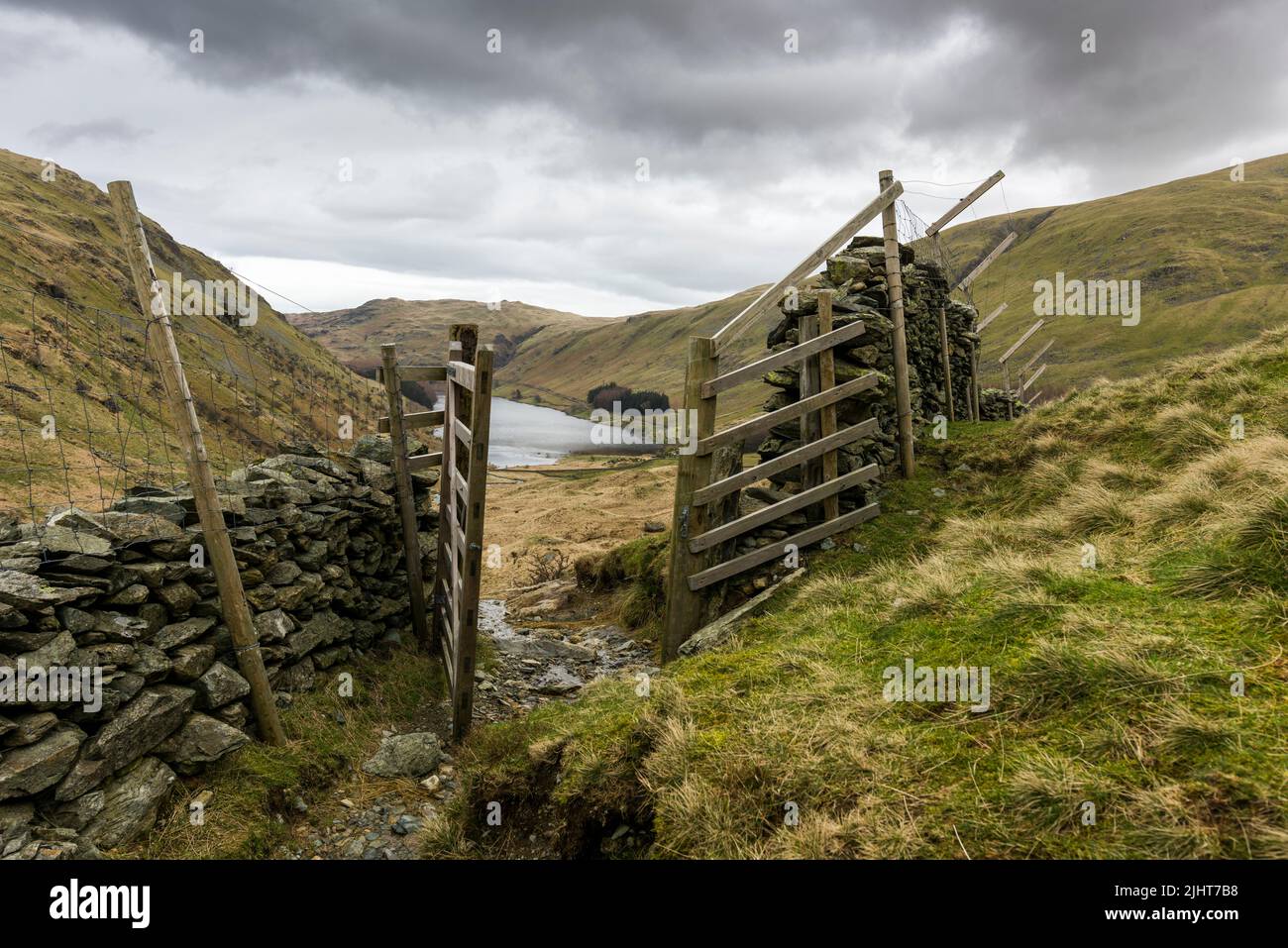 A bridleway through a gate above Haweswater Reservoir at Mardale Head in the Lake District National Park, Cumbria, England. Stock Photo
