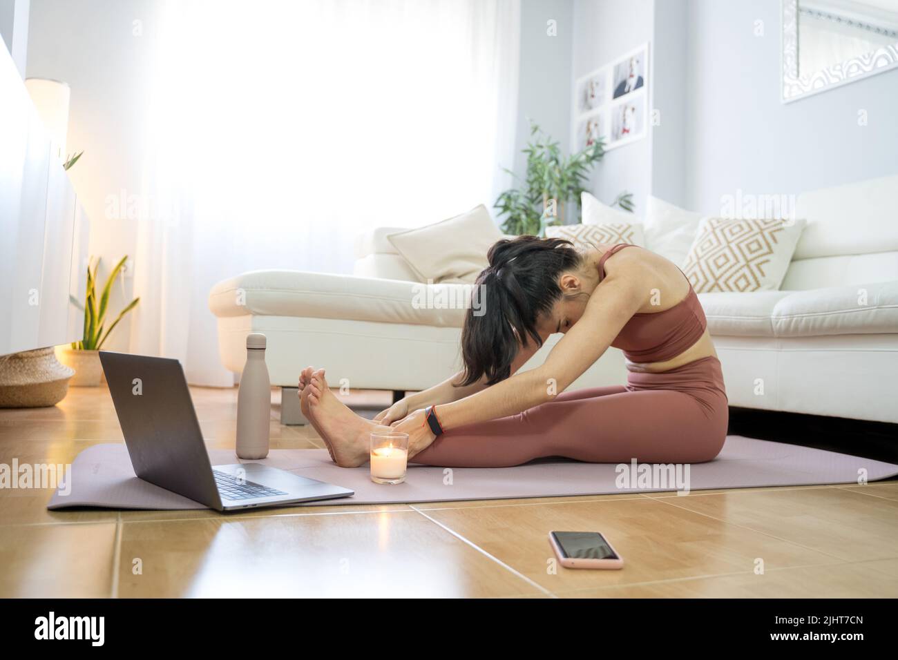 YOUNG GIRL DOING YOGA AND PILATES IN THE LIVING ROOM OF HER HOME WITH ...