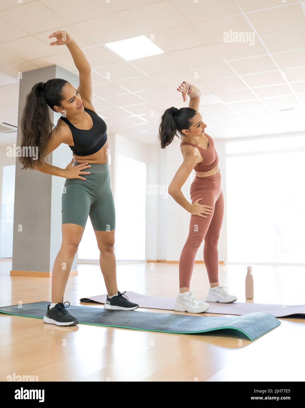 TWO GIRLS TRAINING YOGA AND PILATES TOGETHER WITH A BALL AND WEIGHTS