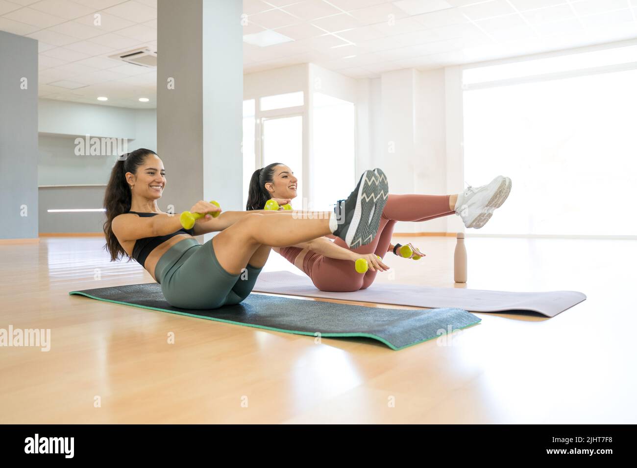 TWO GIRLS TRAINING YOGA AND PILATES TOGETHER WITH A BALL AND WEIGHTS