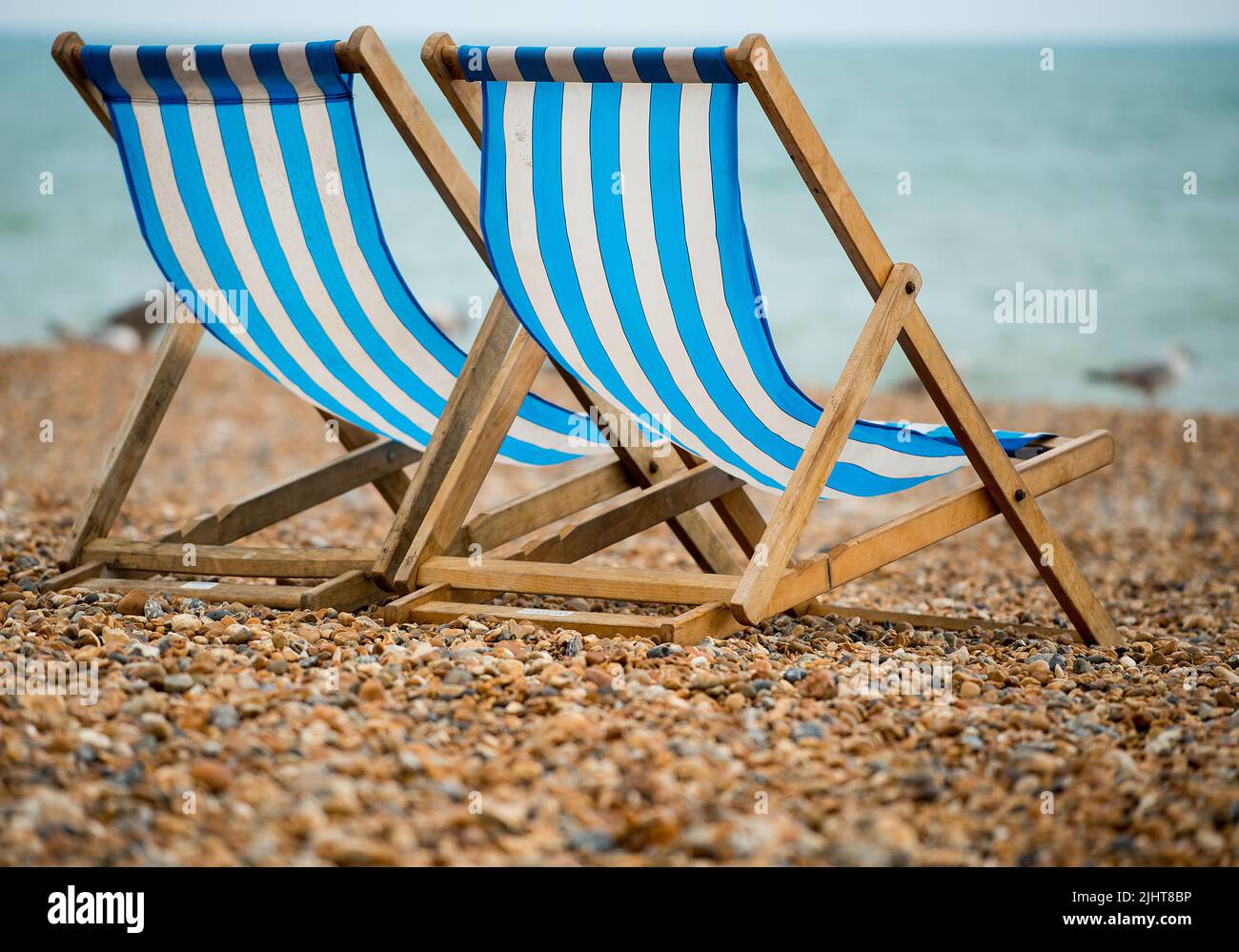Two deck chairs on the pebble beach at Brighton, UK. Stock Photo