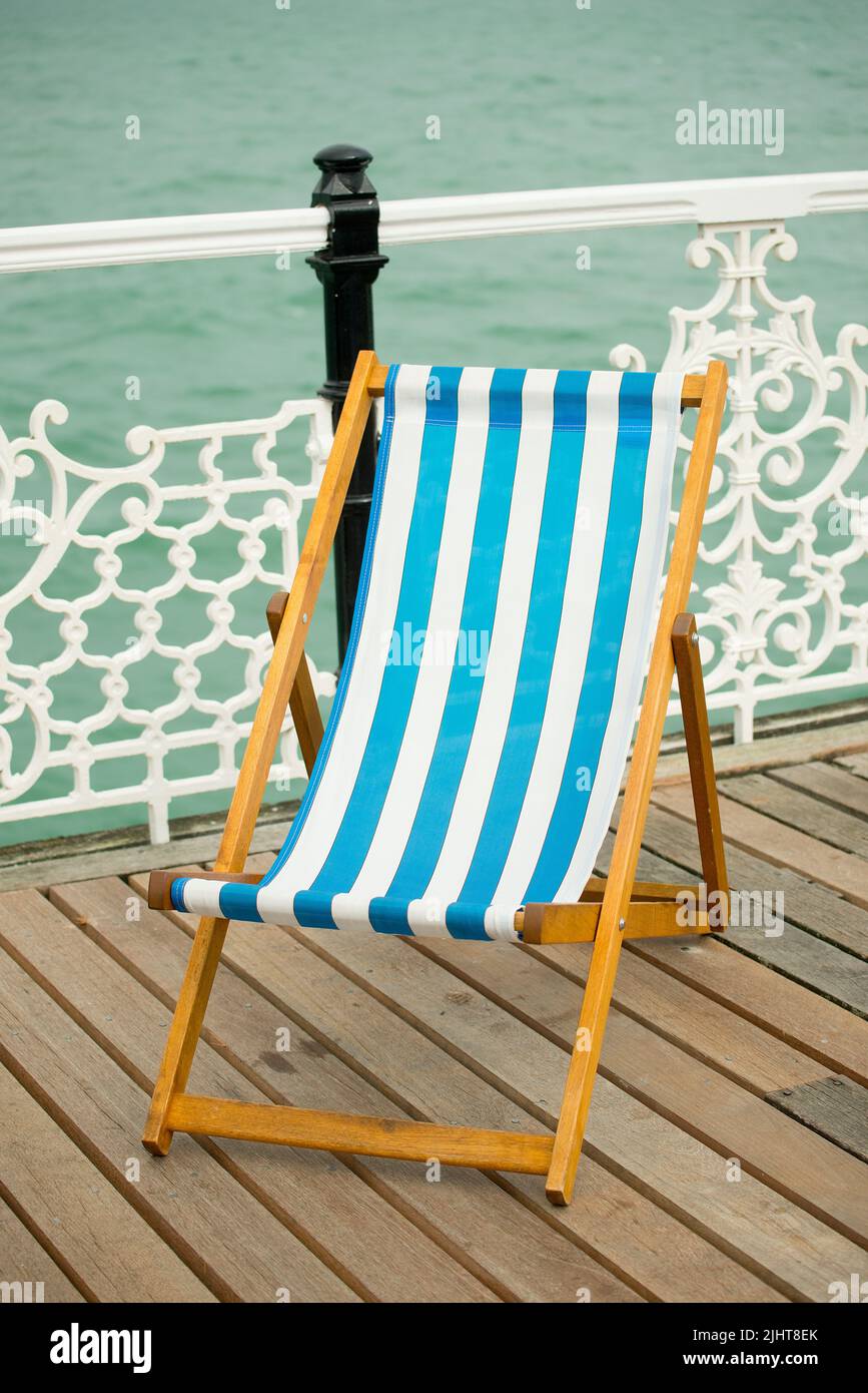 Seaside deck chair on Brighton Pier promenade without people. Stock Photo