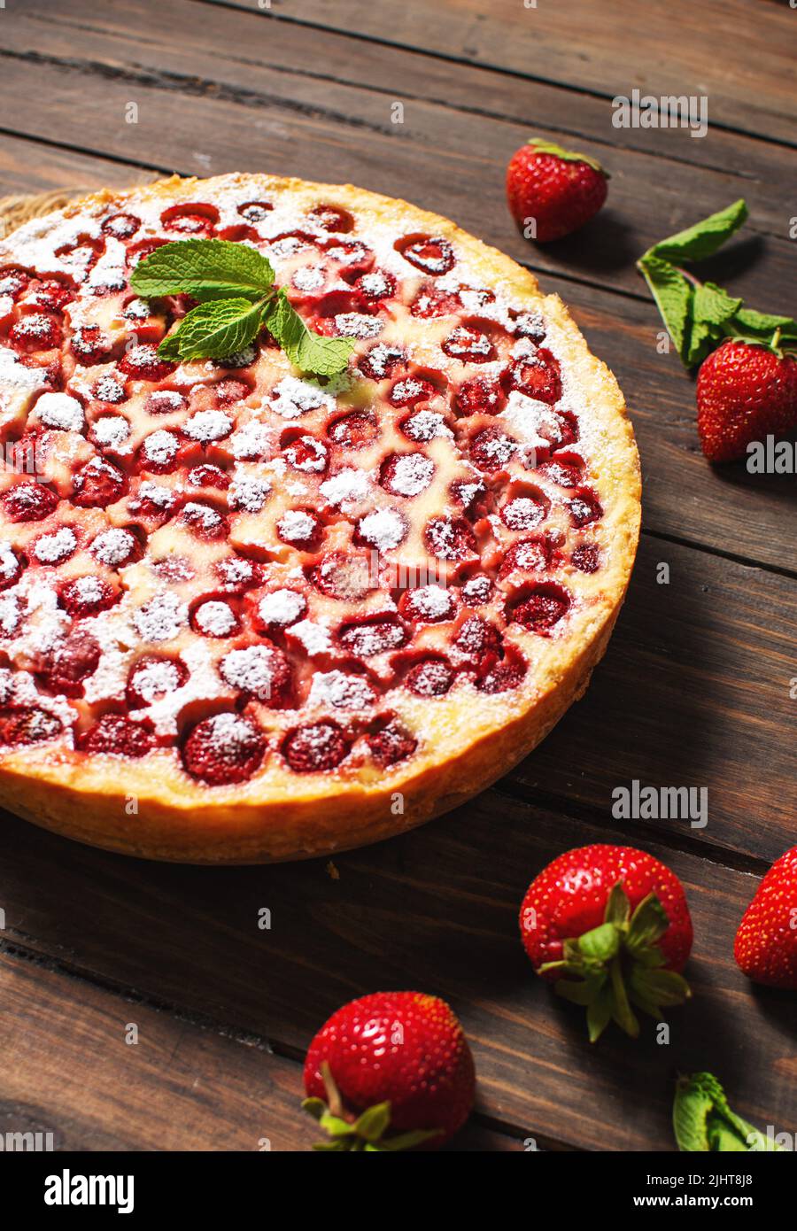 Homemade strawberry custard tart decorated with strawberry on wooden background. Stock Photo