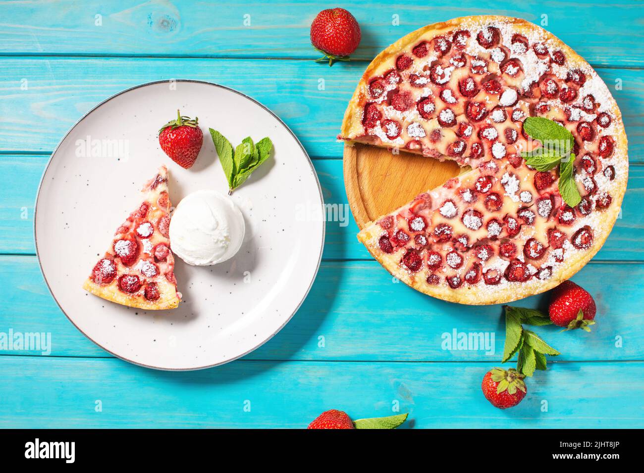 Homemade strawberry custard tart decorated with strawberry and ice cream on blue wooden background. Top view Stock Photo