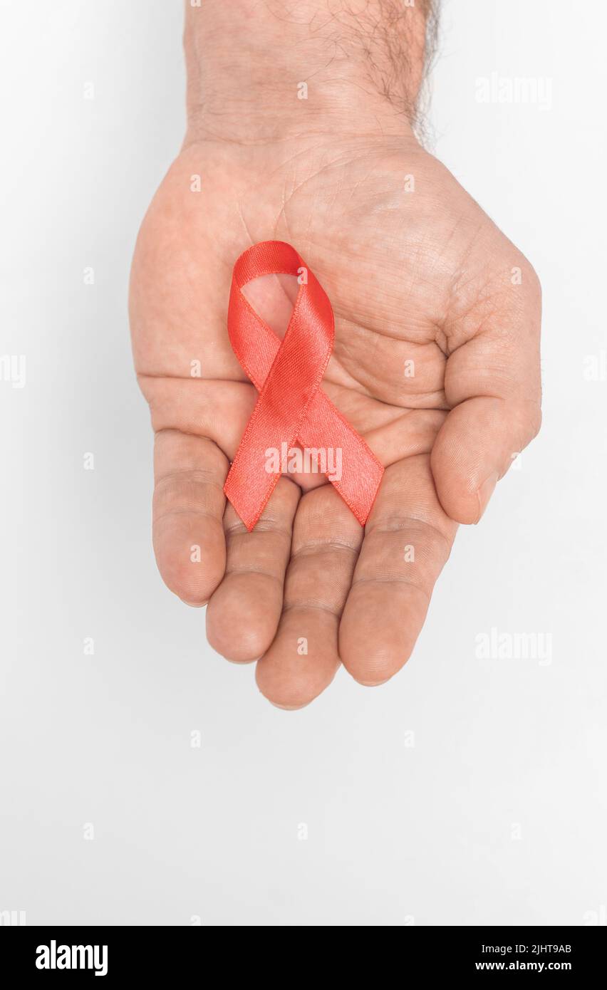 Red ribbon bow awareness on mans hand isolated on white background. HIV, AIDS world day. Social life issues concept. Aids charity fund concept. Healthcare and medicine concept.  Stock Photo