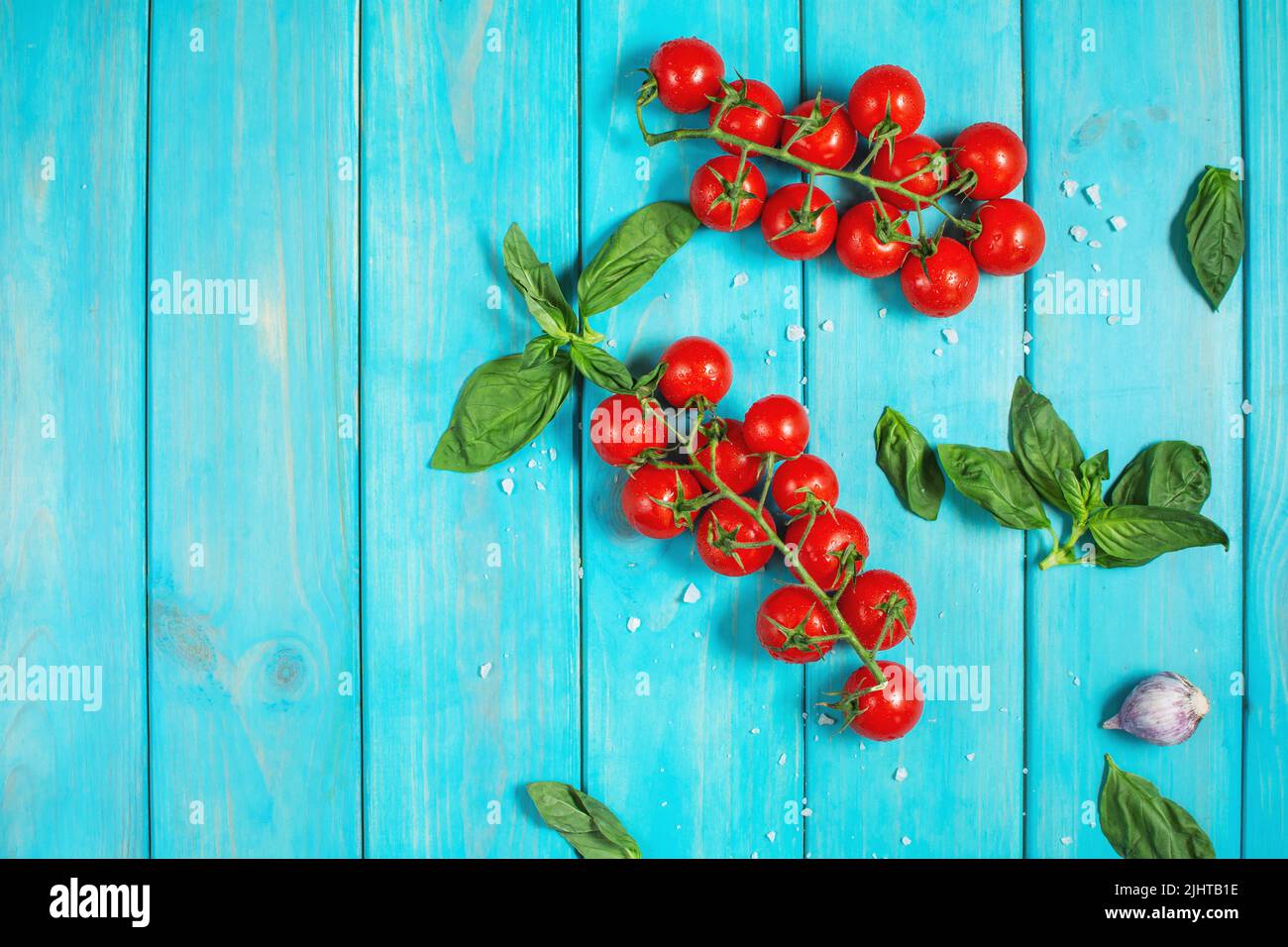 Fresh cherry tomatoes and basil with spices on a blue wooden background . Top view and copy space Stock Photo
