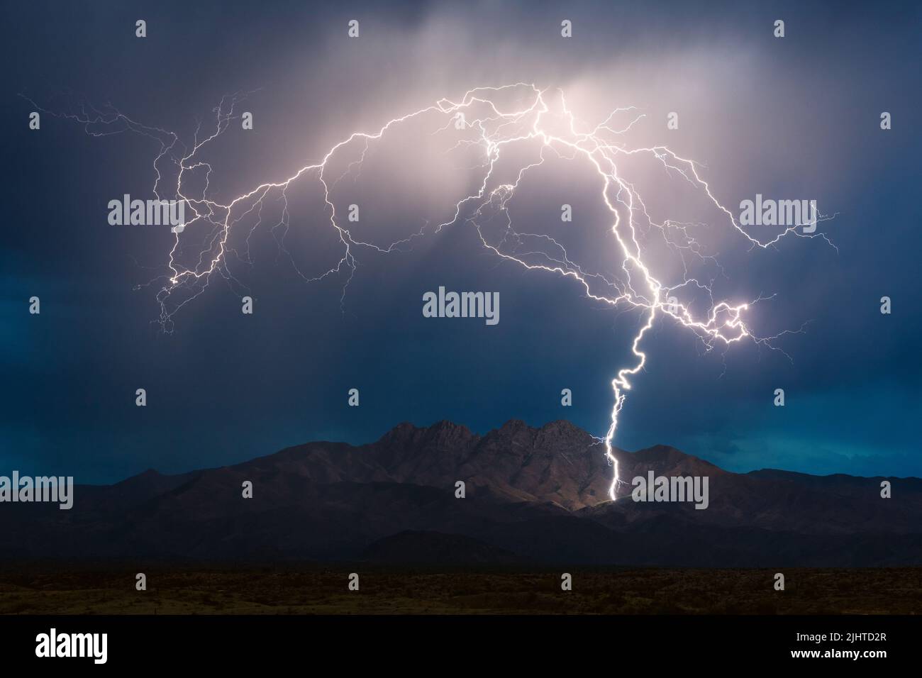 A massive lightning bolt strikes the Four Peaks in the Mazatzal Mountains during a monsoon thunderstorm in Arizona Stock Photo