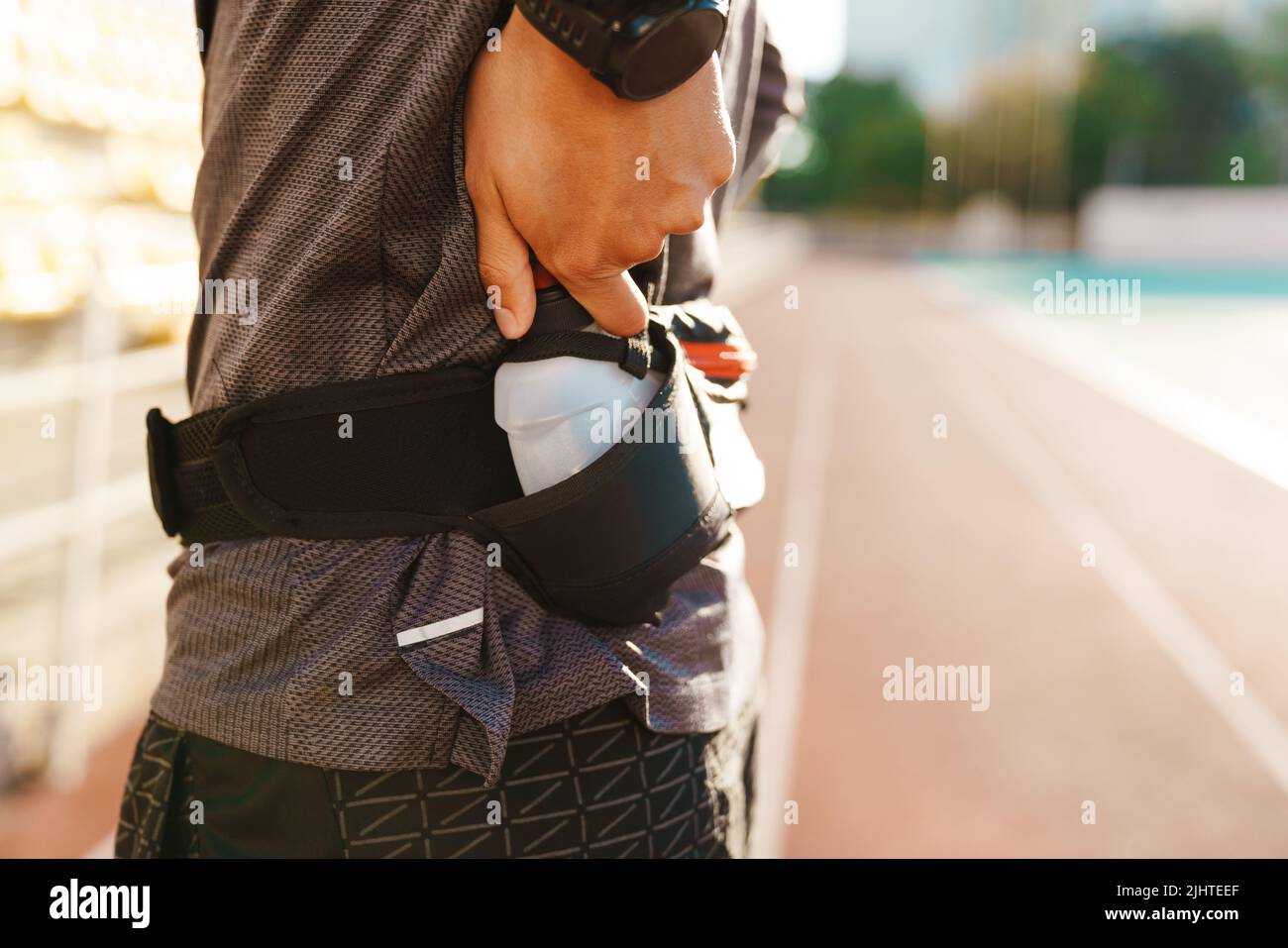 Young white sportsman drinking water while working out on stadium