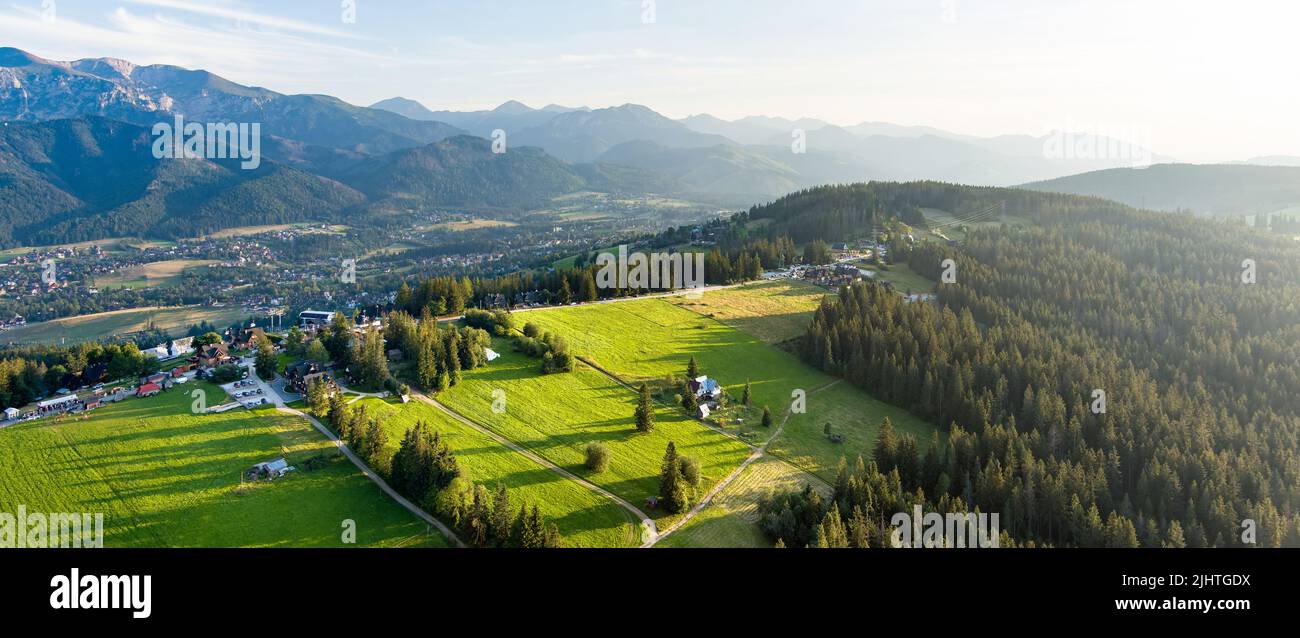 Aerial view of Zakopane town underneath Tatra Mountains taken from the Gubalowka mountain range. High mountains and green hills in summer or spring. S Stock Photo