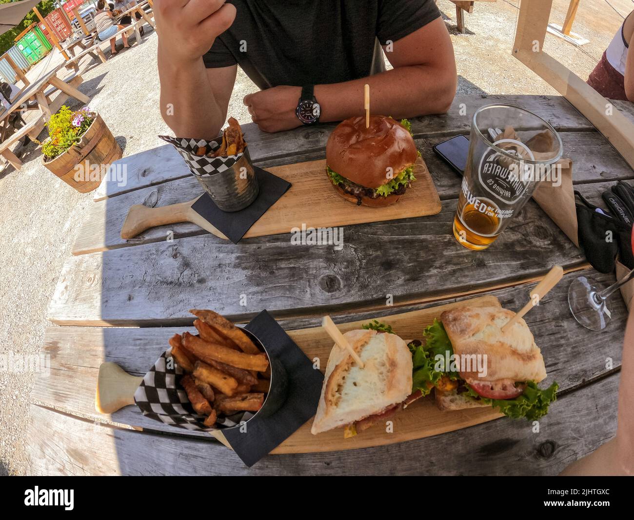 Point of view of young friends eating burgers, sandwiches at restaurant patio after work - Friendship concept with happy people enjoying time together Stock Photo