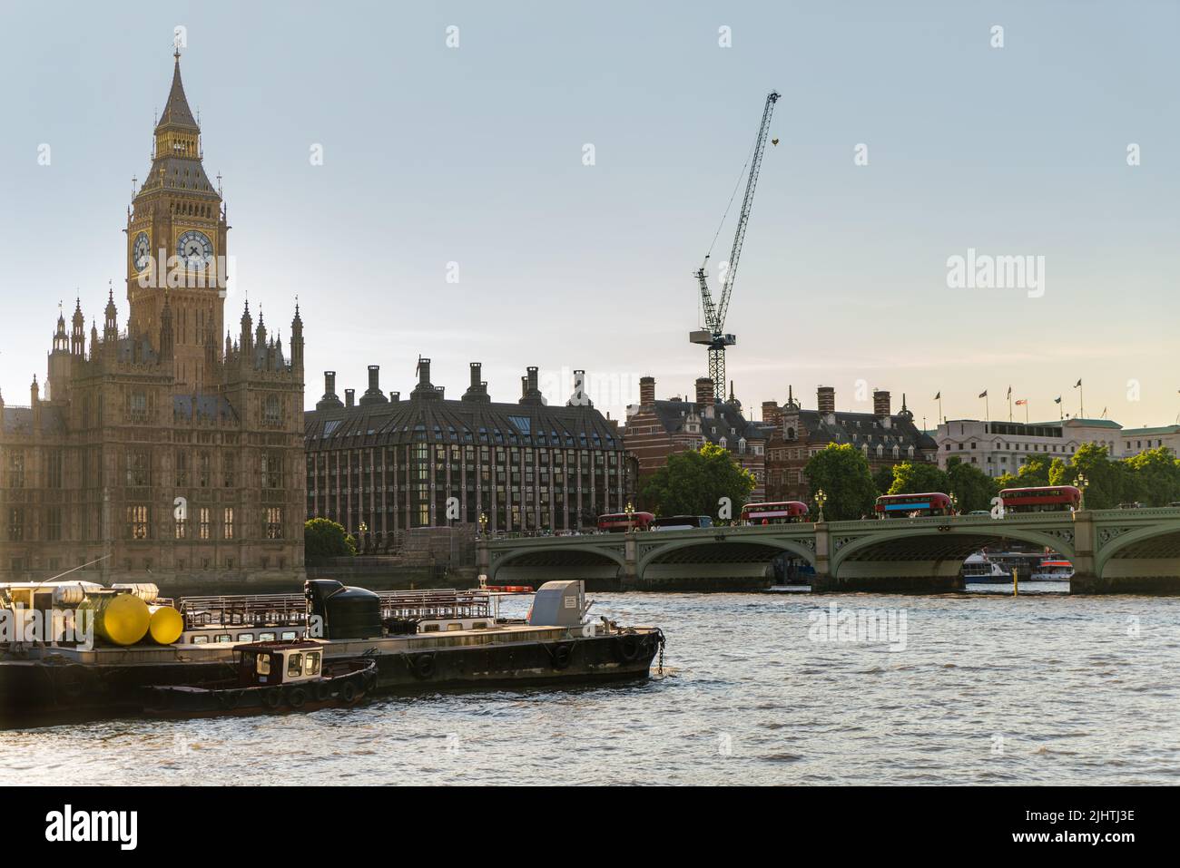 The Houses of Parliament, Big Ben and Red Buses on Westminster Bridge over The River Thames at dusk in London, England Stock Photo