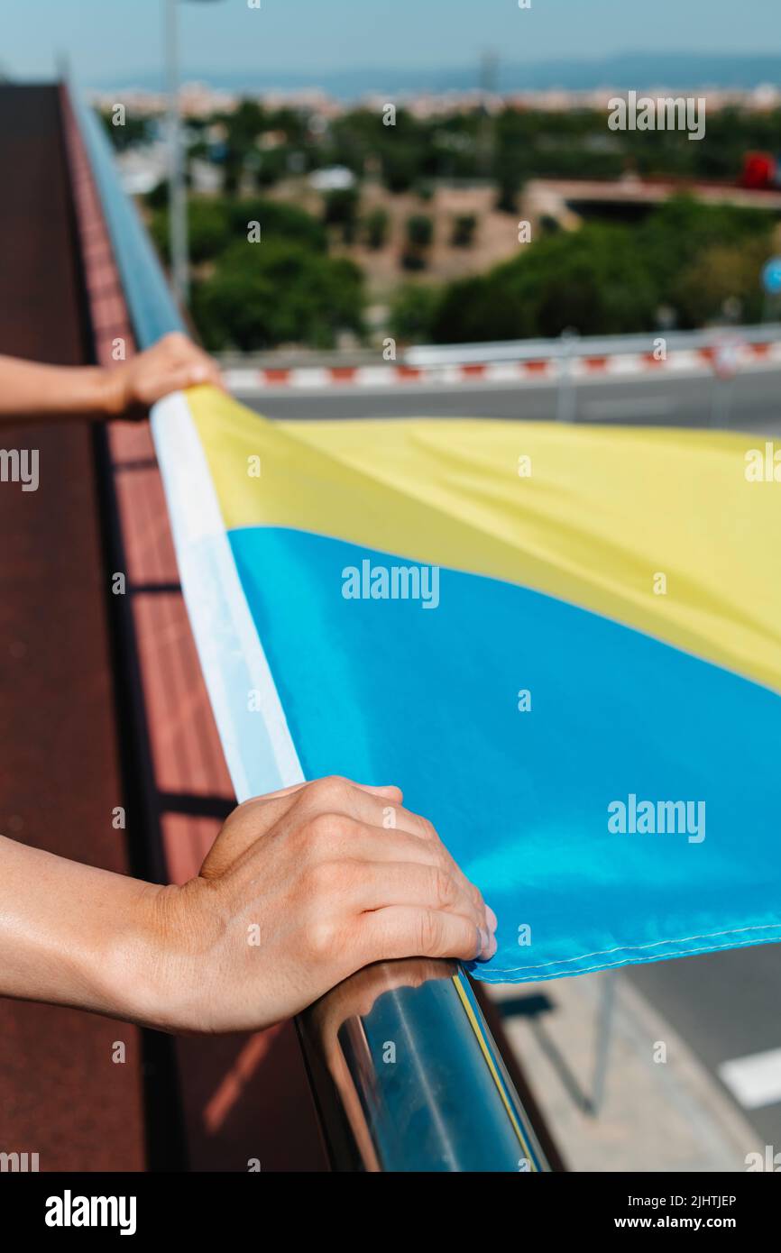 closeup of a man holding the ukrainian flag on the railing, outdoors Stock Photo