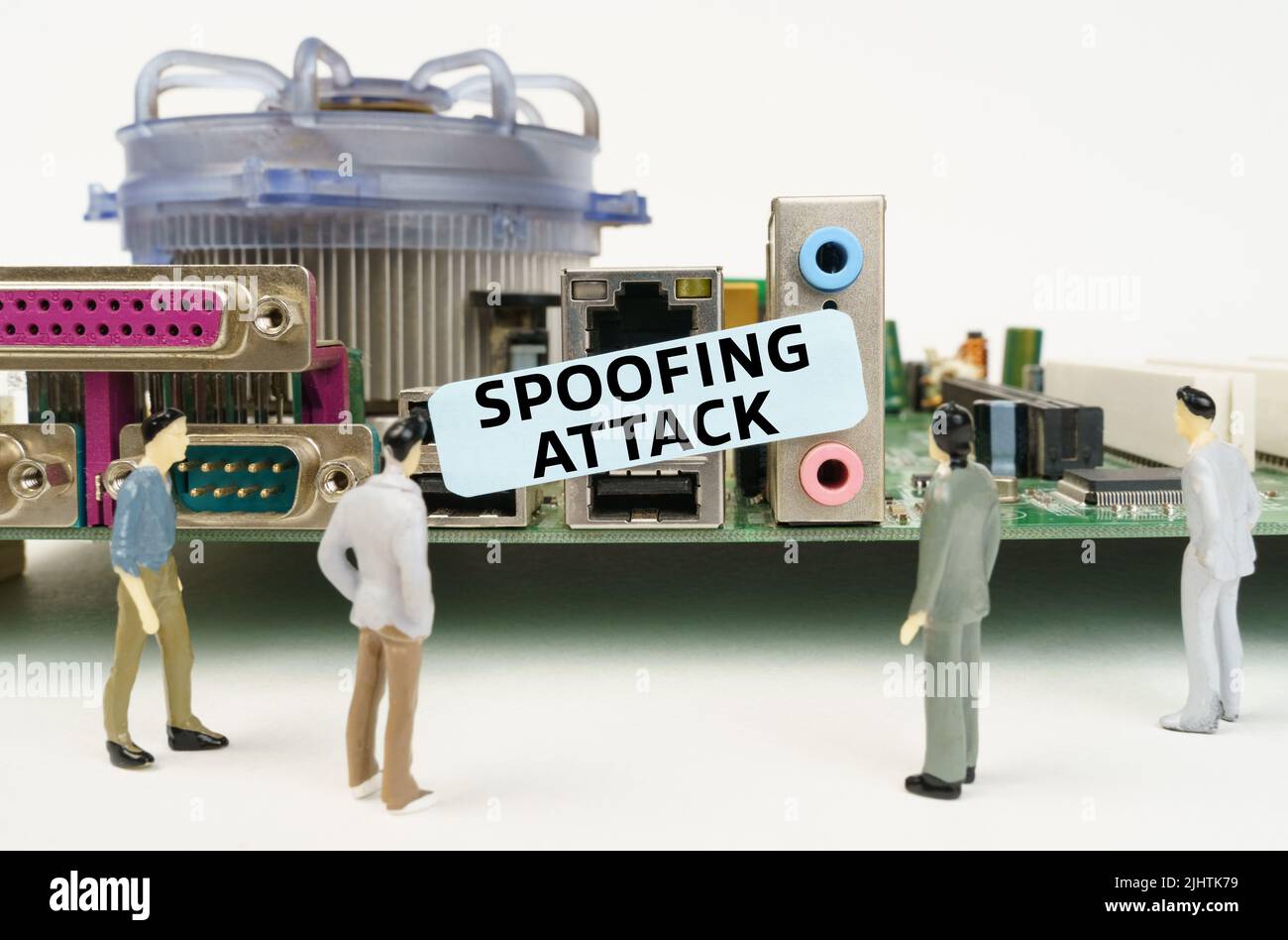 Technology and computer concept. Figures of people are standing near the motherboard and looking at the sticker with the inscription - Spoofing Attack Stock Photo