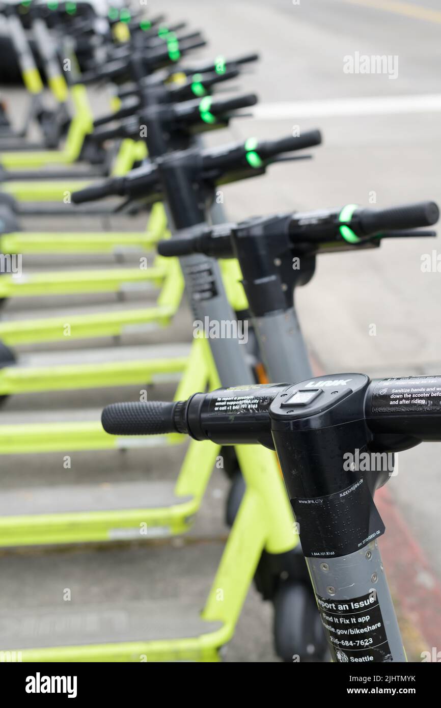 Seattle - July 18, 2022; A row of LINK electric scooters stand upright along a street in Seattle Stock Photo