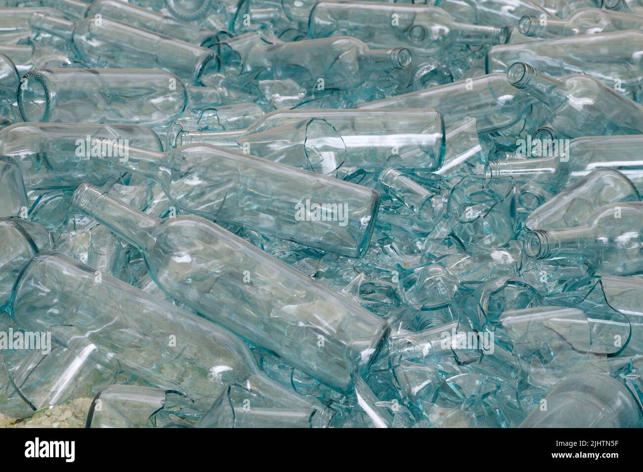 Large pile of blue tinted glass bottles with some broken at a recycling plant scattered in a random pile Stock Photo