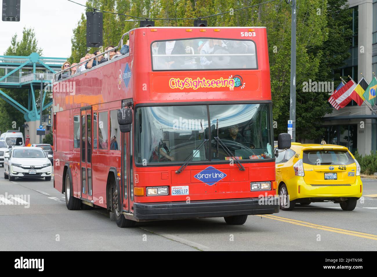 Seattle - July 17, 2022; A City Sightseeing red double decker bus by Gray Line travels the Seattle waterfront with happy tourists Stock Photo