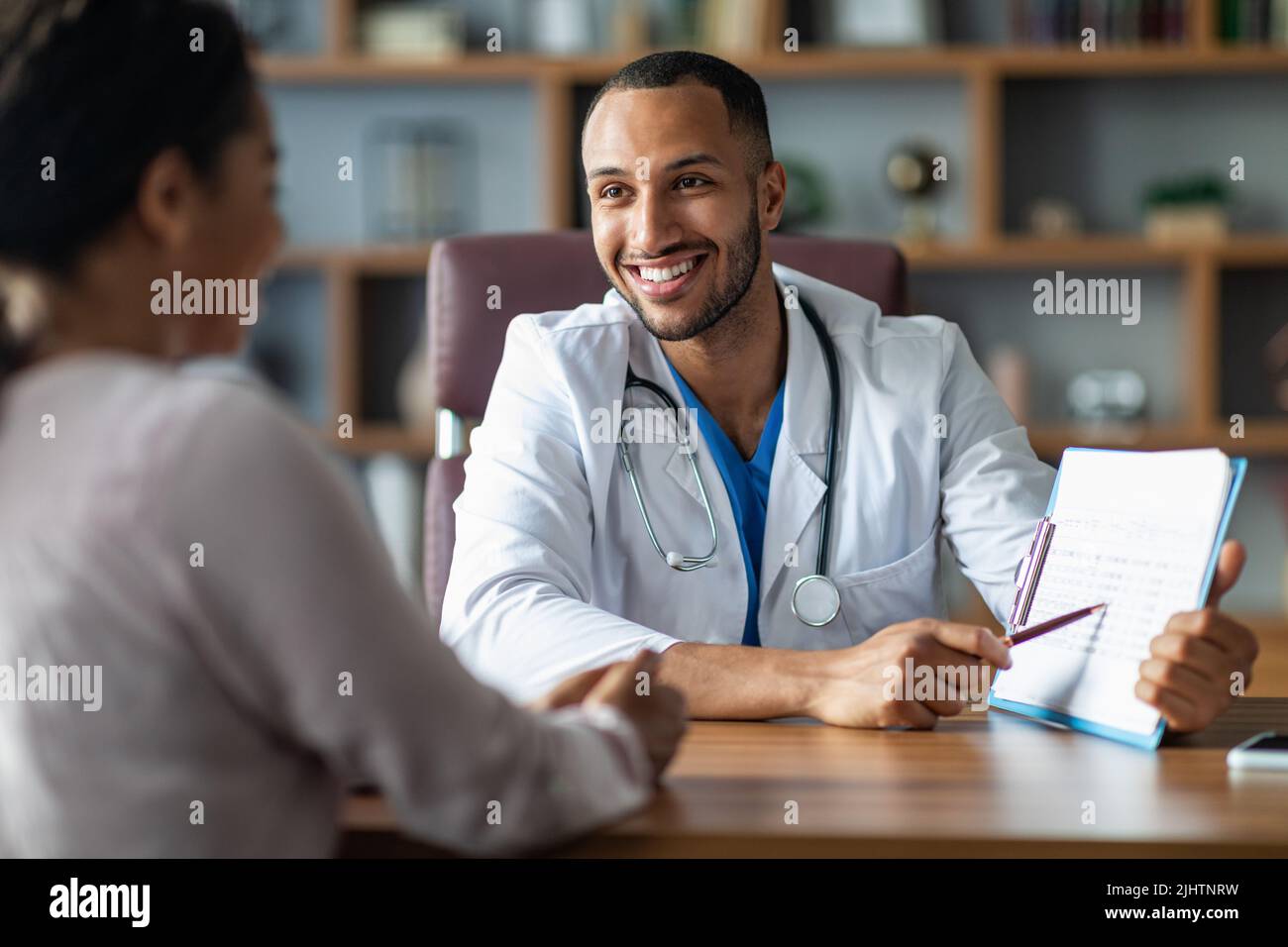 Cheerful doctor showing black lady patient treatment plan Stock Photo