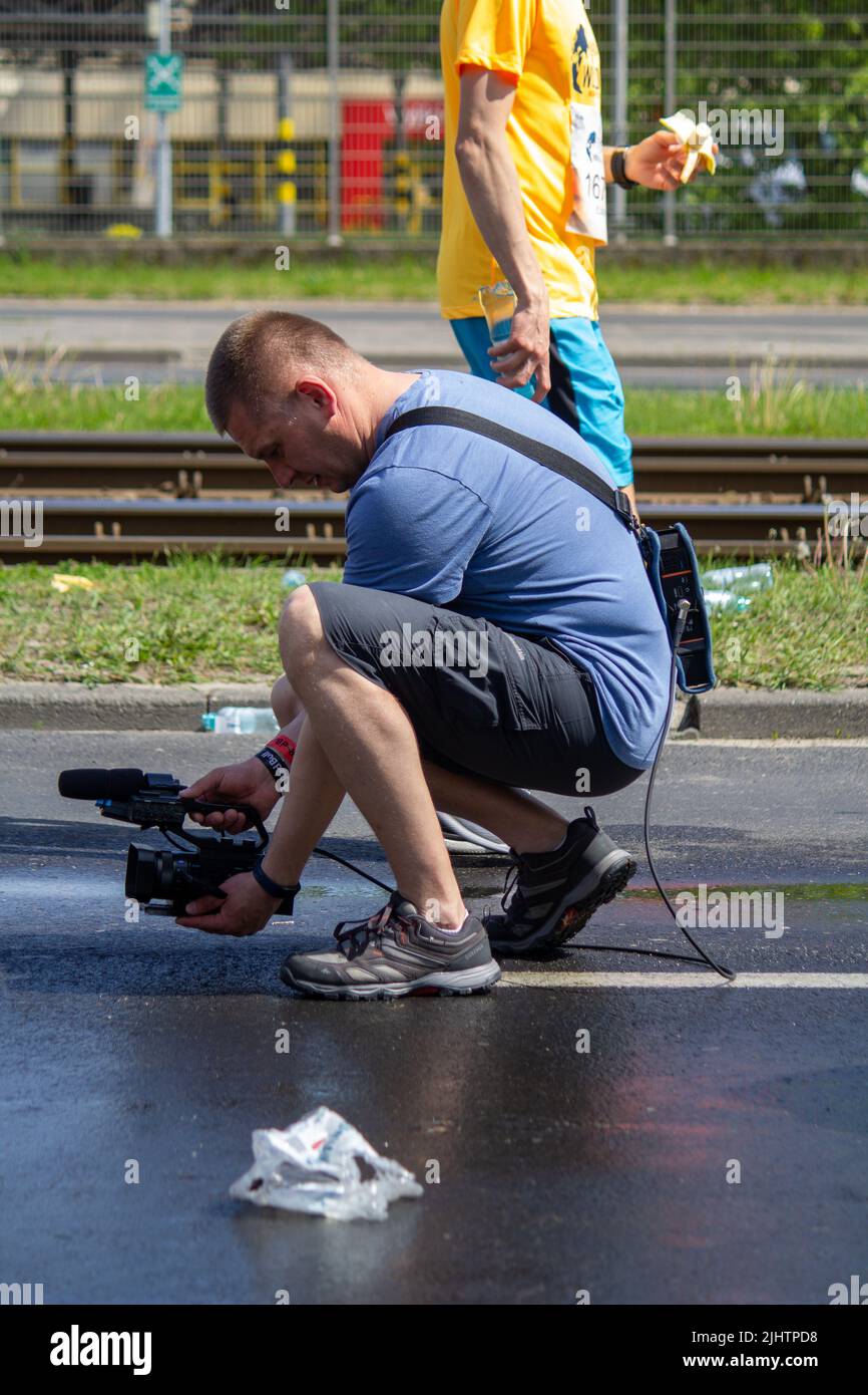 A photographer with camera filming the runners at Wings for Life World Run Stock Photo