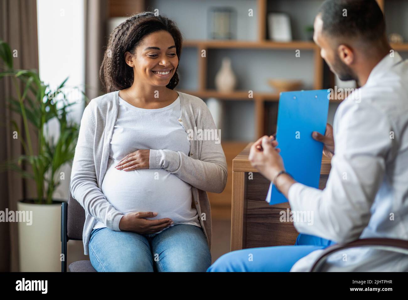 Pregnant black woman visiting doctor at private clinic Stock Photo