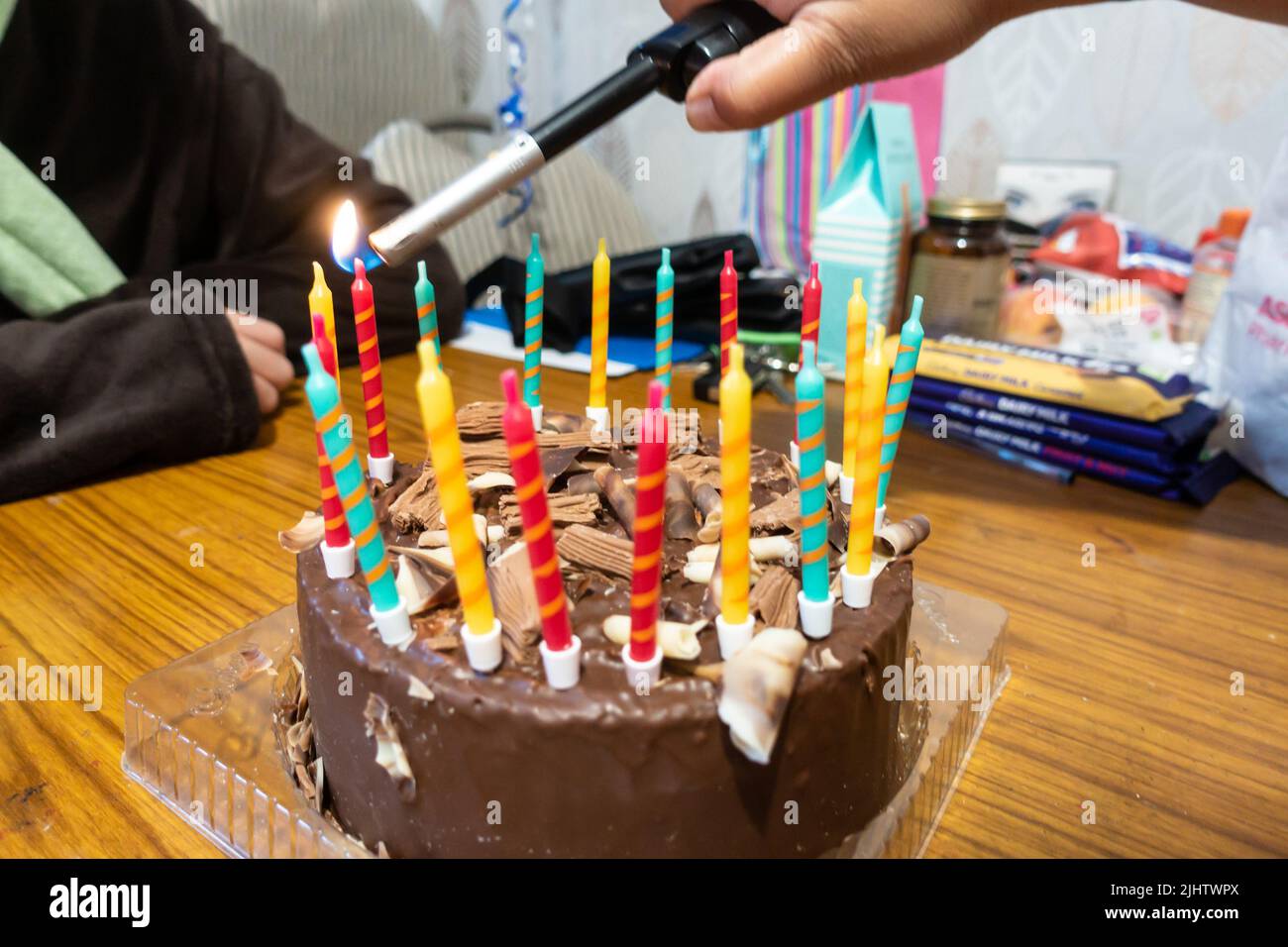Candles on a chocolate birthday cake lit using a gas lighter Stock