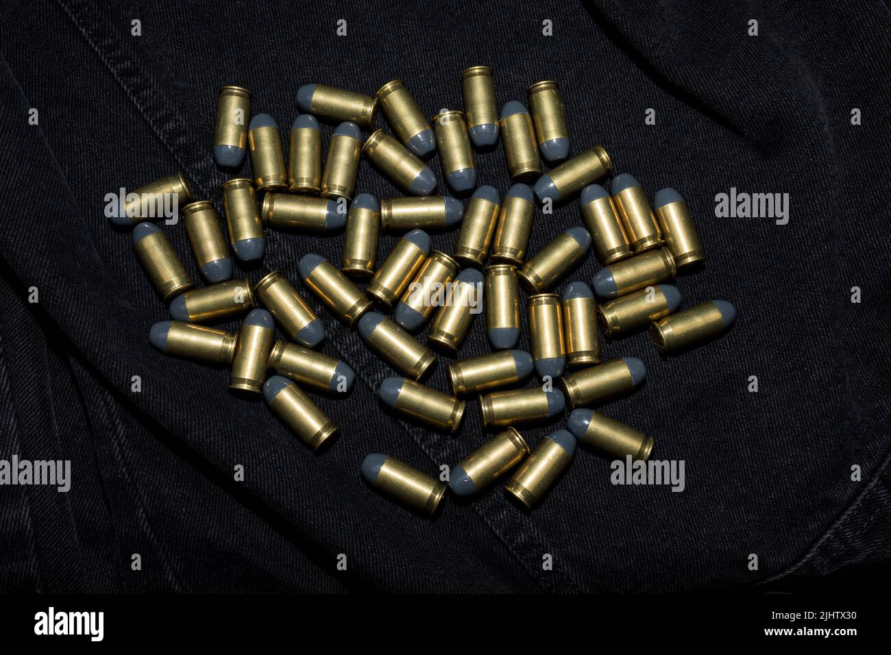 Many .45 ACP cartridges on a black fabric background Stock Photo