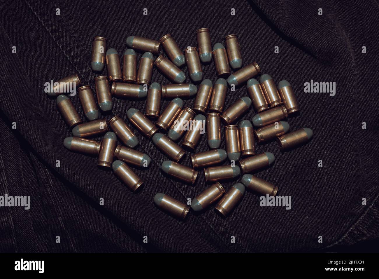 Many .45 ACP cartridges on a black denim background Stock Photo