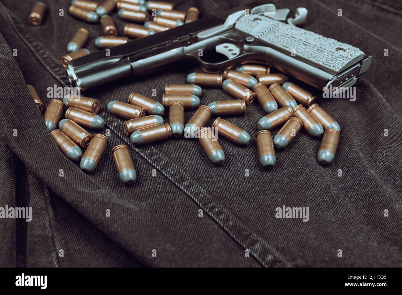 Model 1911 pistol and cartridges (.45 ACP) on a black denim background Stock Photo