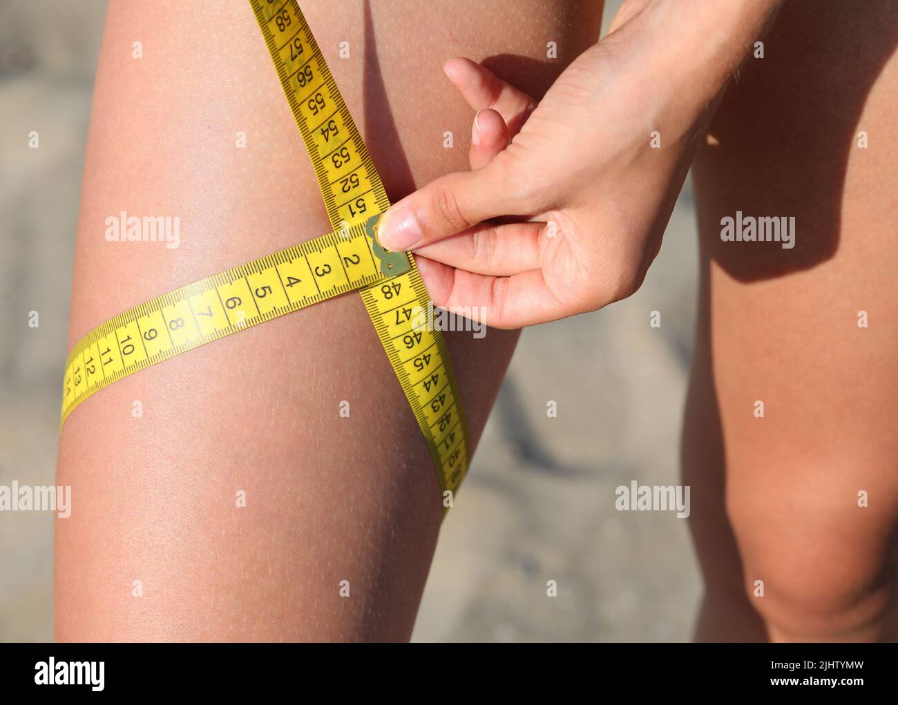 thigh of the young girl while measuring the circumference with a tape meter Stock Photo