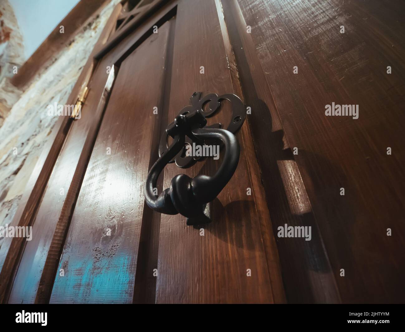 Old-fashioned vintage steel knocker handle on old wooden door close up. Stock Photo