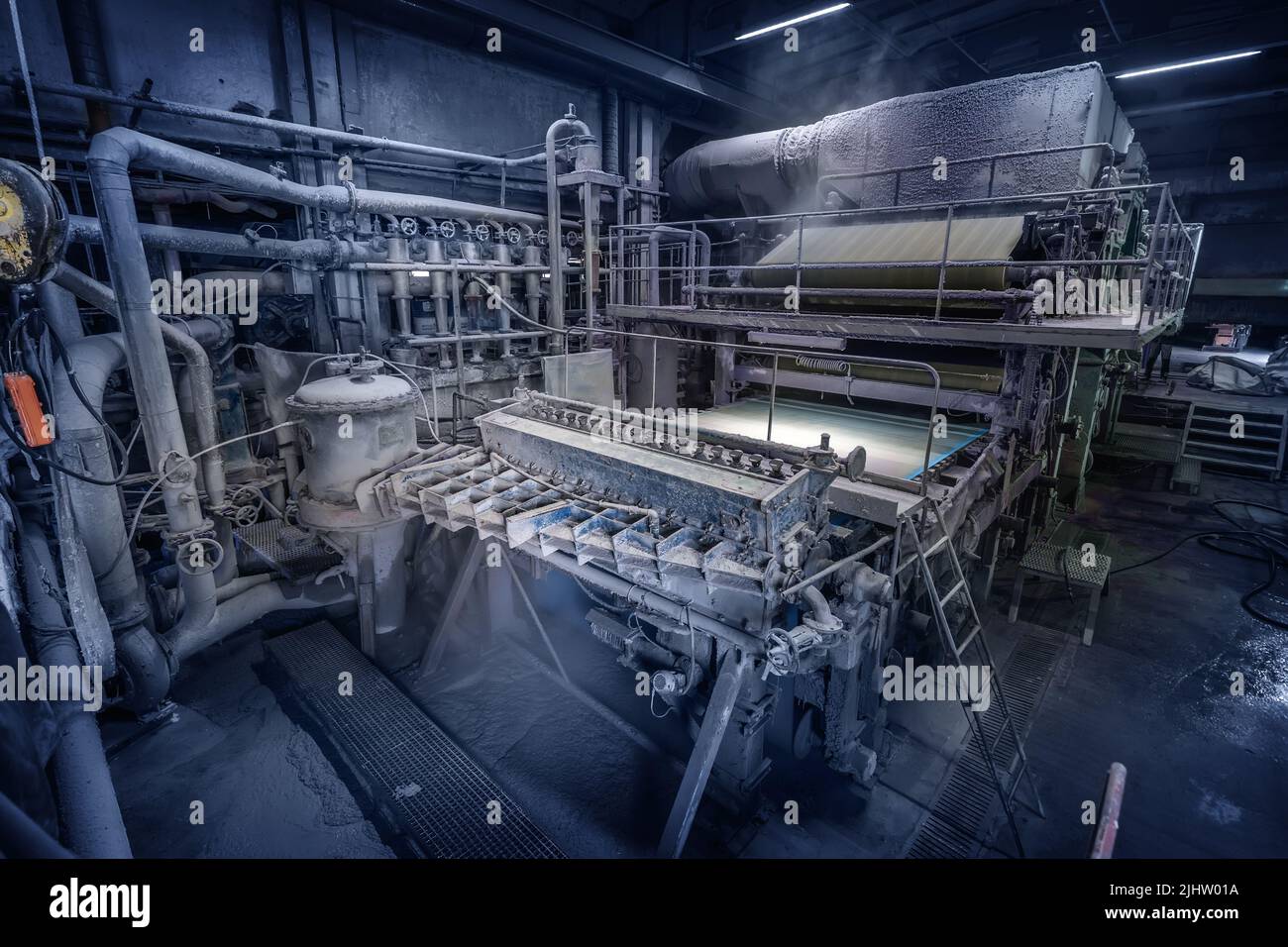 Production machine with rolls of new paper in waste paper recycling factory. Stock Photo