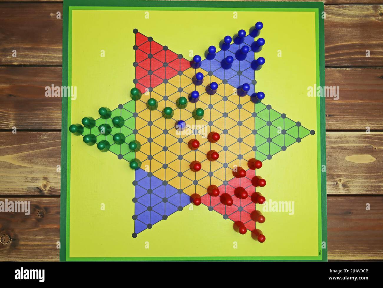 Top down view on isolated yellow gamboard with hexagon, multicolored game pieces, wooden background - chinese checkers (sternhalma) Stock Photo