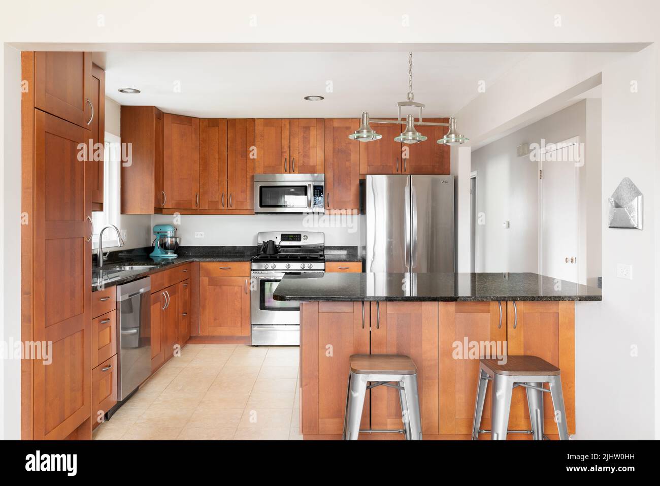 A large kitchen with wood cabinets and island, black granite ...