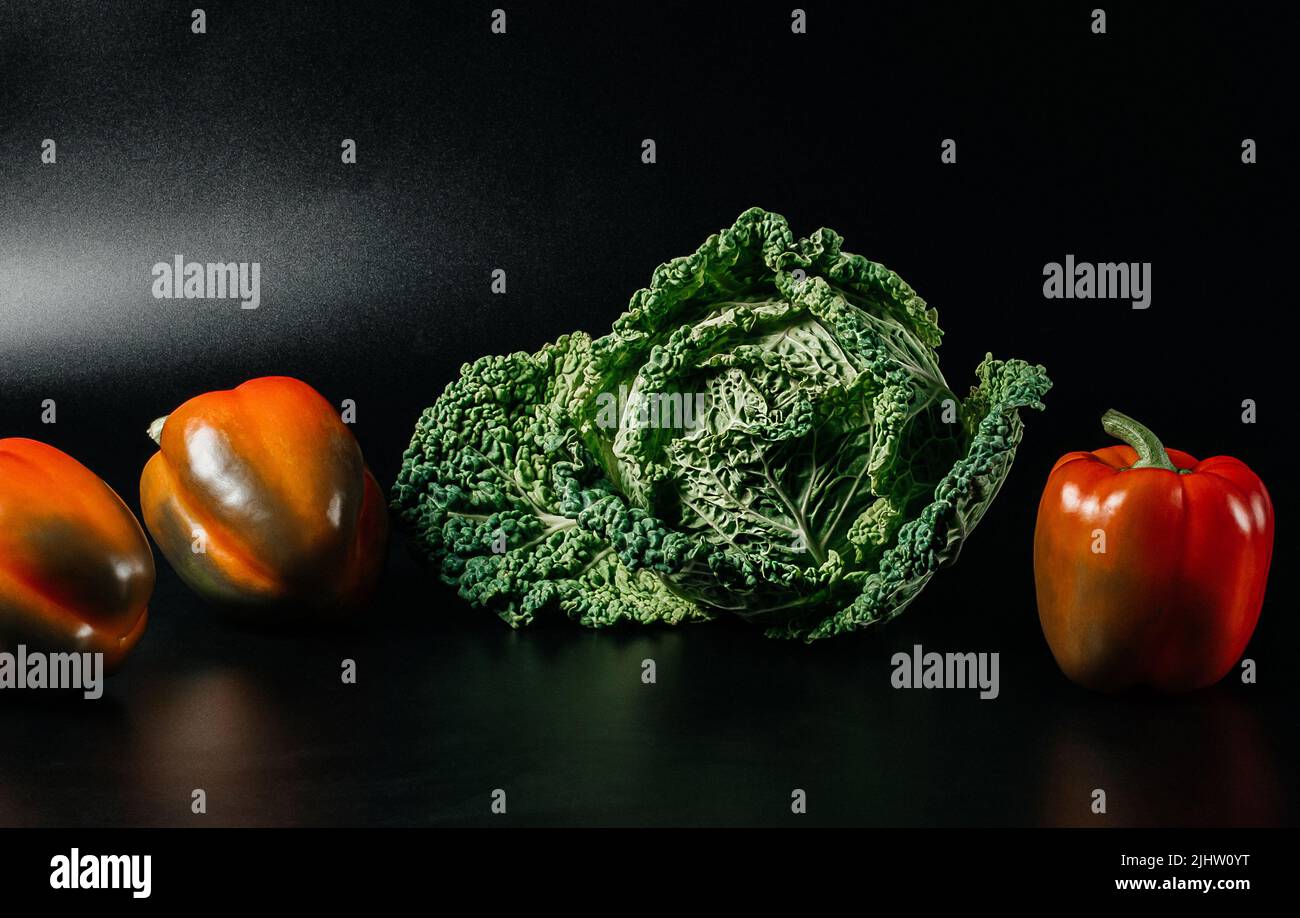 Fresh savoy cabbage and paprika on black background. Top view detox