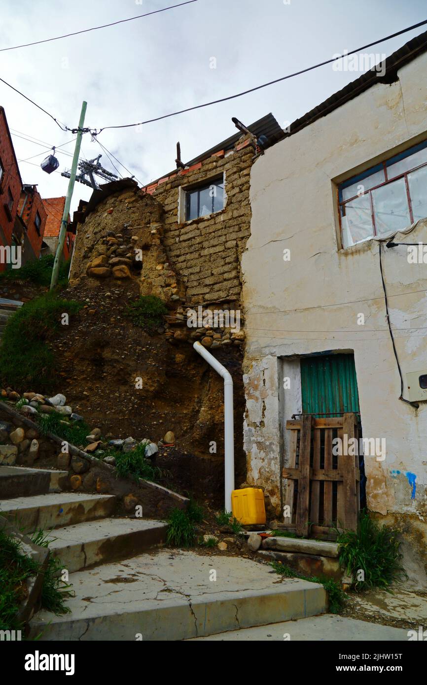 La Paz, Bolivia: A poorly built adobe / mudbrick house with unsafe drainage system causing water filtration and soil erosion of the foundations in Tembladerani / Cotahuma district. Many of La Paz's hillside neighbourhoods have been built in unstable areas without proper permits or building controls. Subsidence and erosion causing landslides and houses to collapse are common, especially in the rainy season. Stock Photo